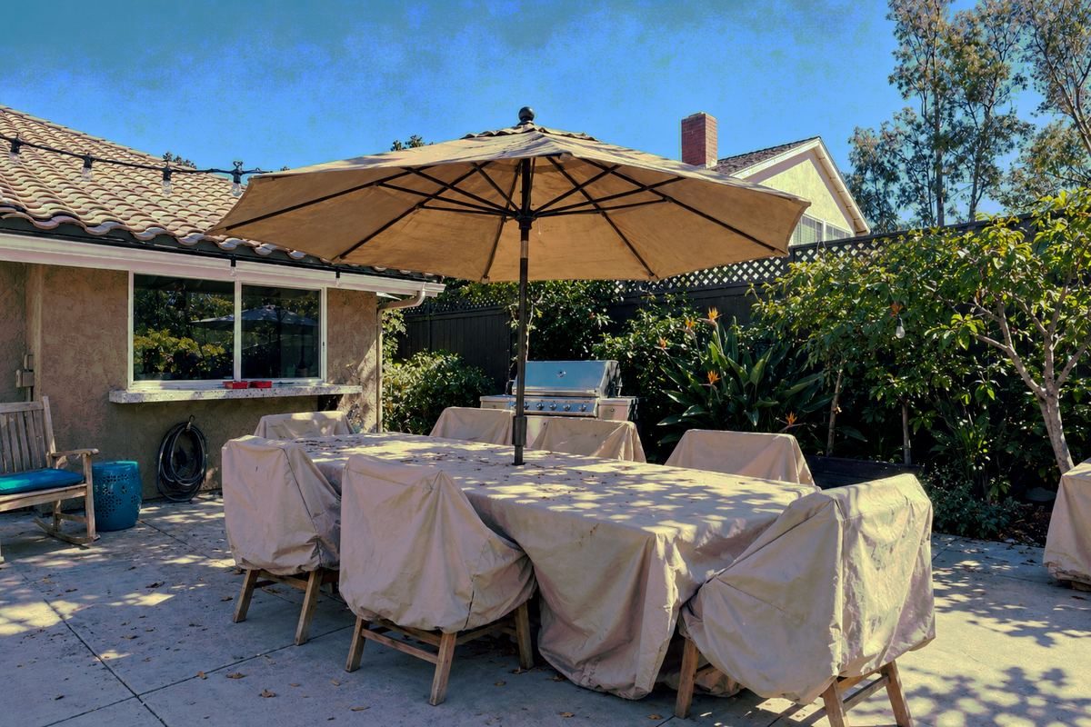 The backyard before: a bare concrete patio with covered furniture