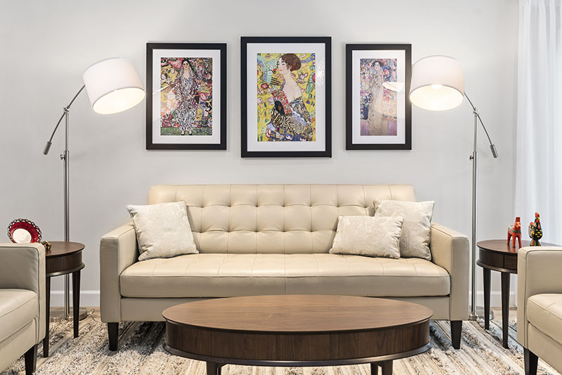 Living room with a tufted sofa beneath three framed floral prints