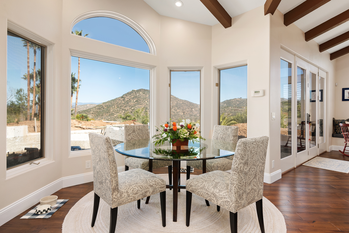 Breakfast nook with a round glass table and tall windows looking out at the hills
