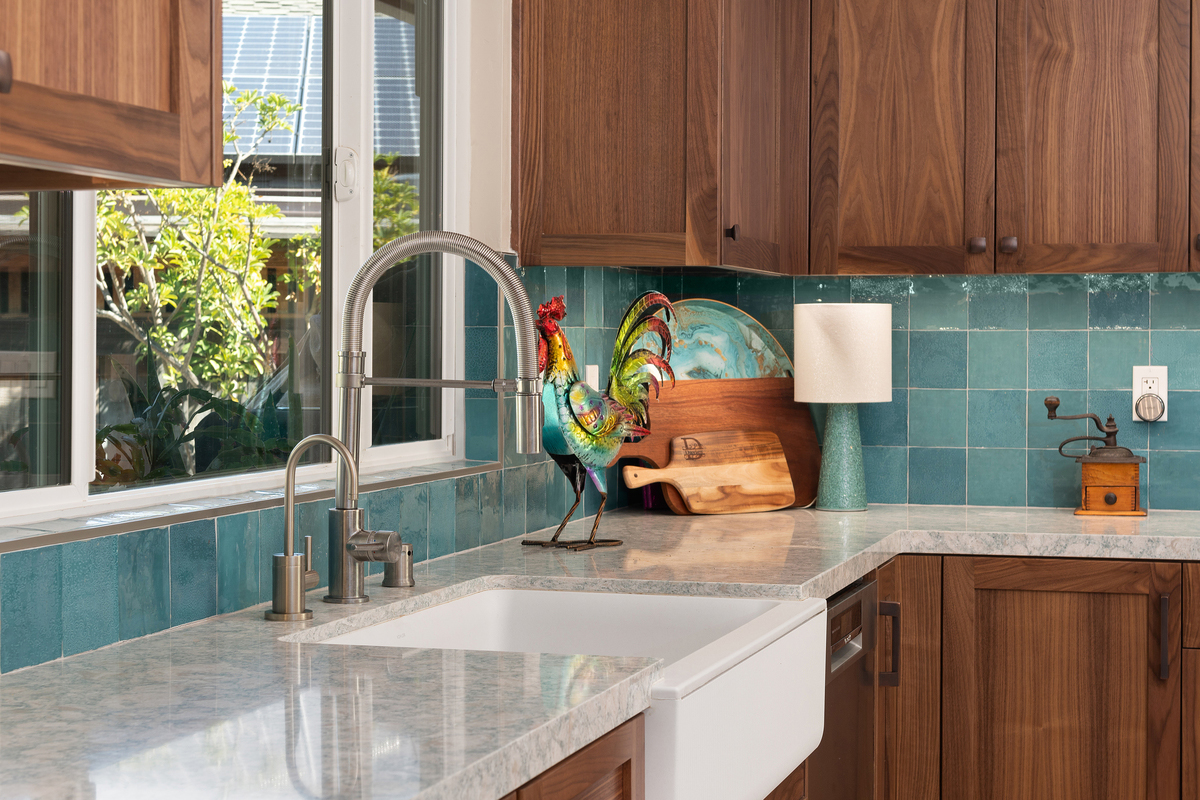 Close-up of a farmhouse sink, quartz counter and handmade turquoise tile backsplash