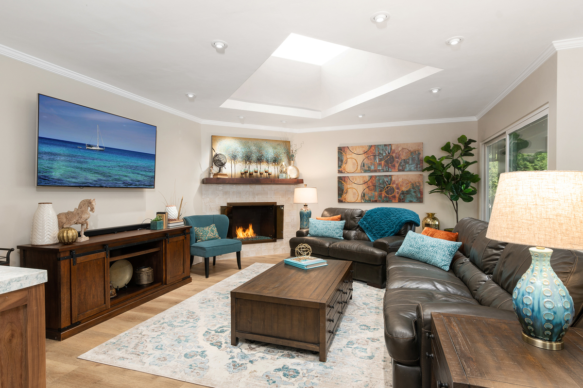 Family room with a leather sectional, fireplace and ocean artwork