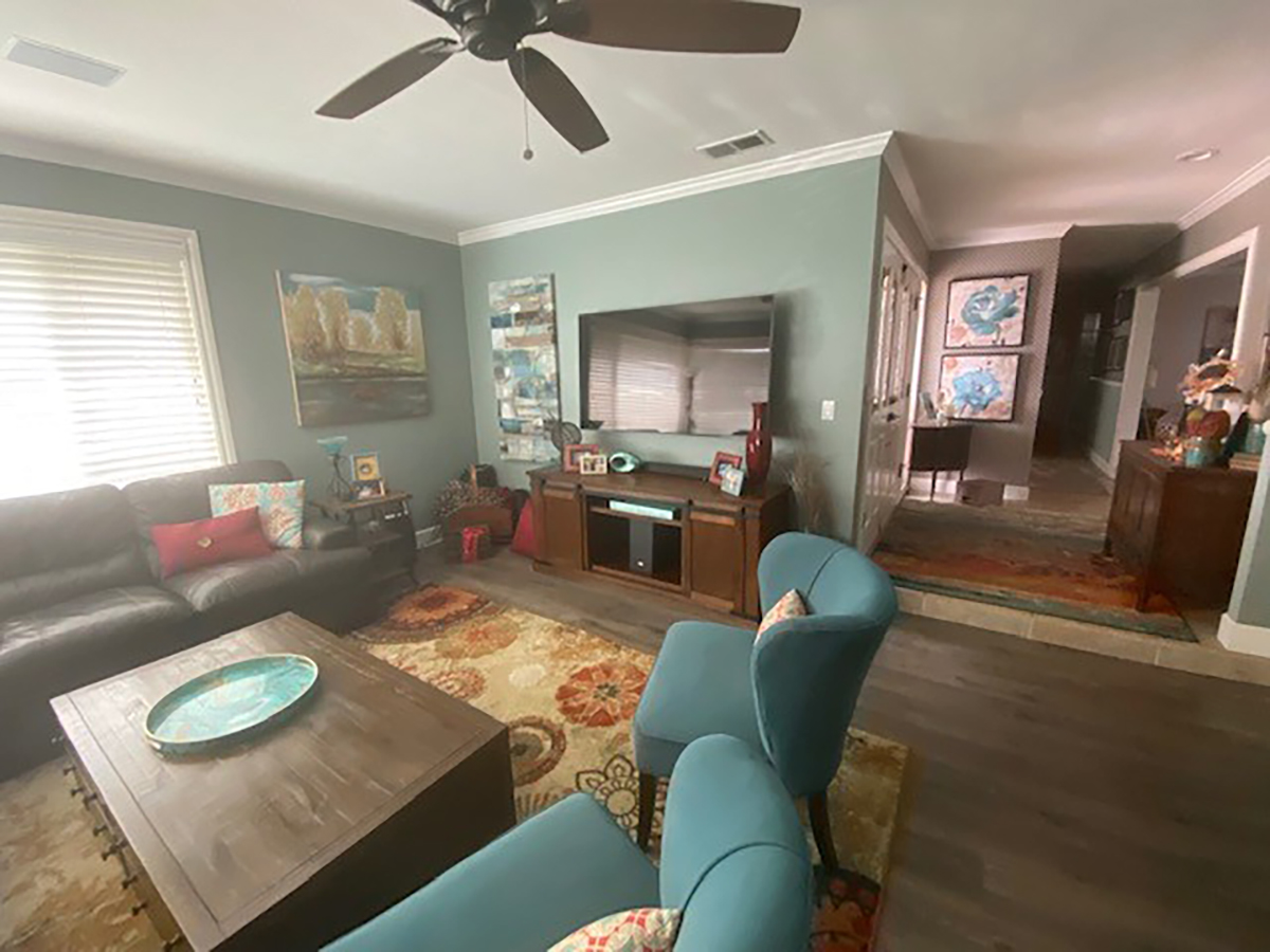 A family room before its remodel, with a leather sofa, teal chairs and a patterned rug