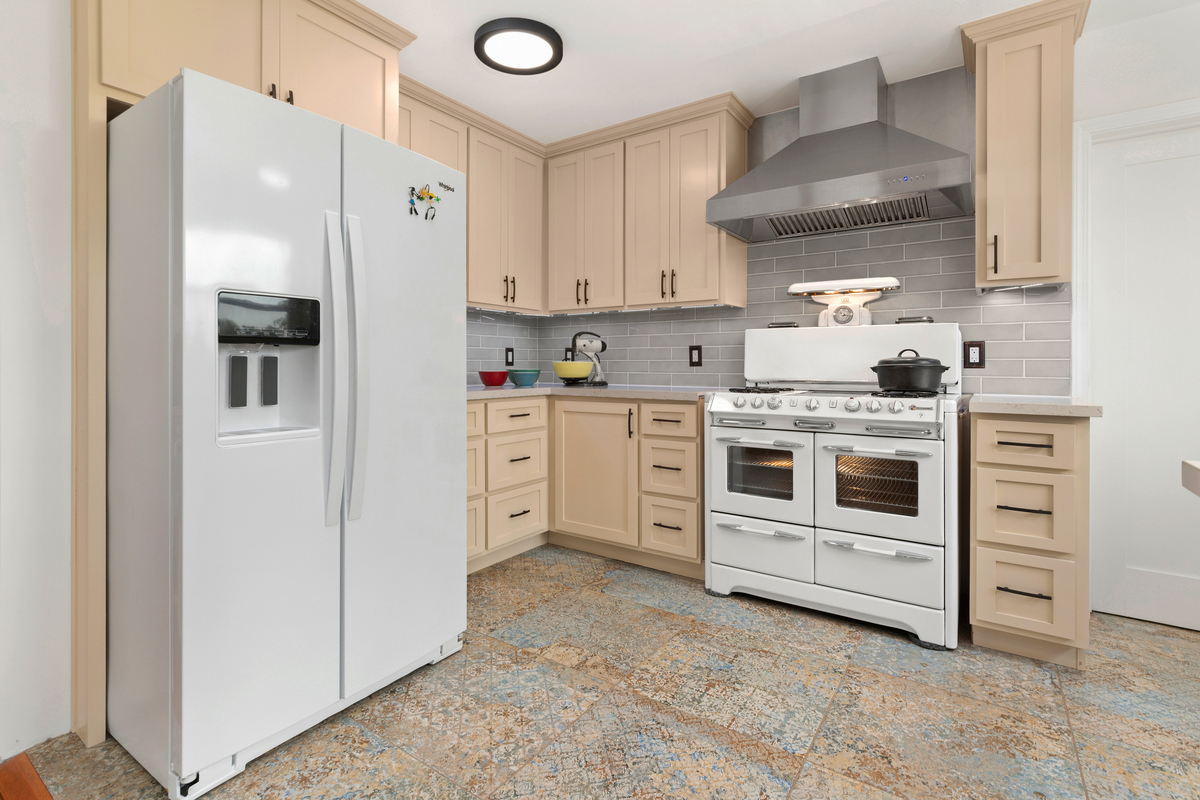 Light kitchen with cream cabinets, a vintage white range and a stainless hood