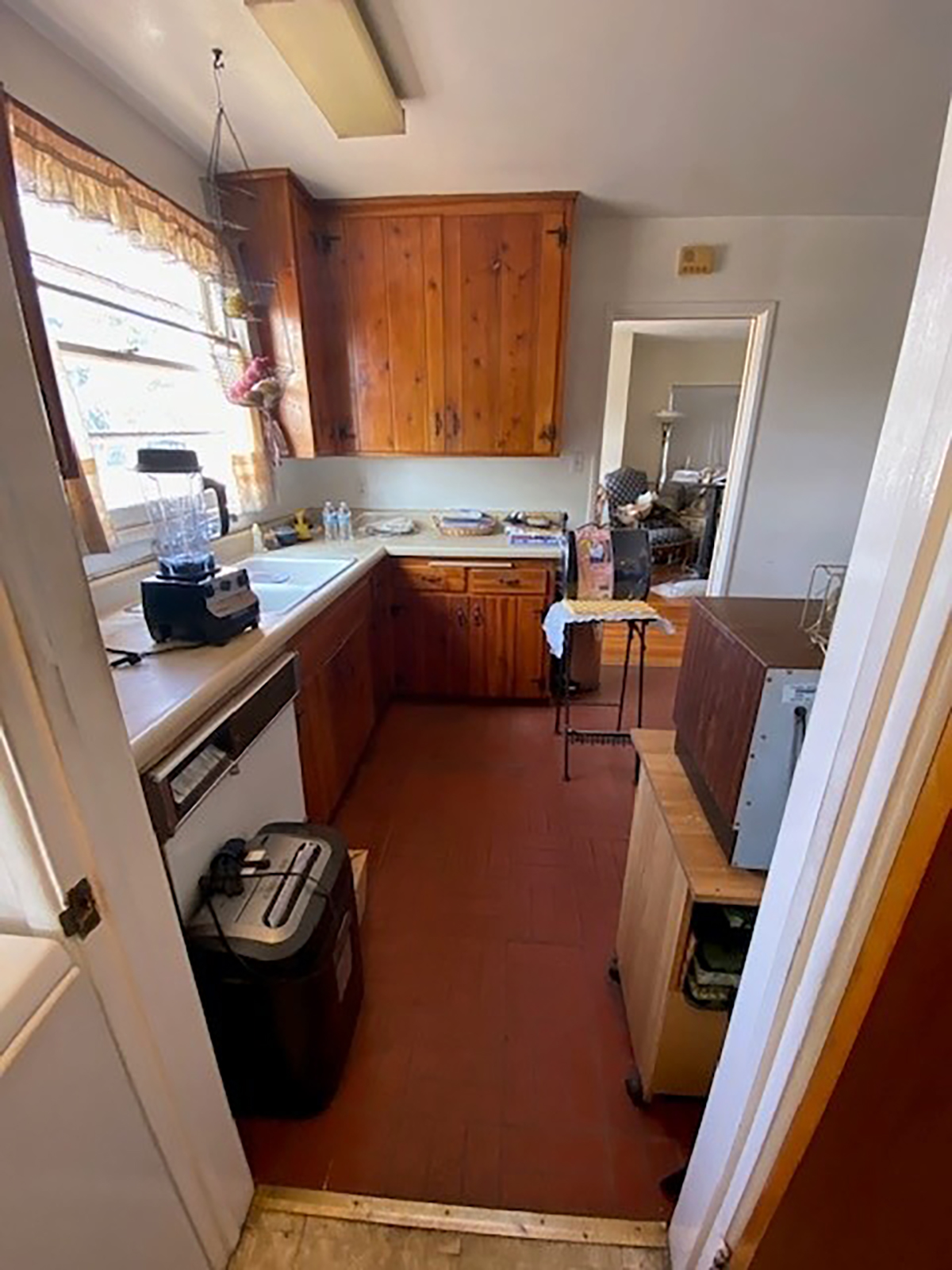 The kitchen before, cramped with dark wood cabinets and red floors