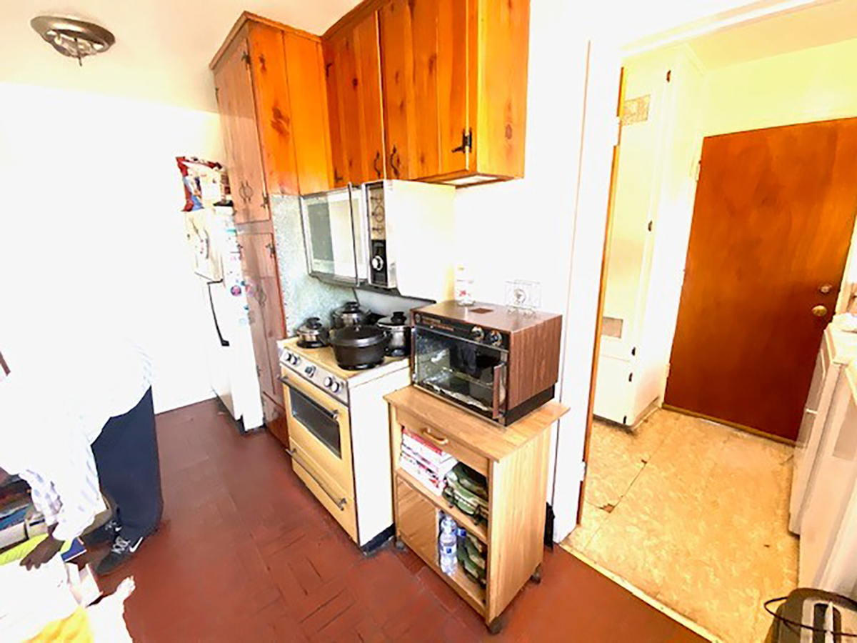 The kitchen before: knotty pine cabinets, red tile floor and a cramped layout