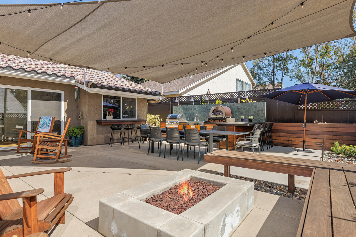Covered backyard patio with a gas fire pit, built-in bar and dining area