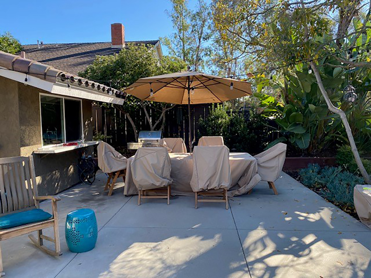 The backyard before: a bare concrete patio with covered furniture