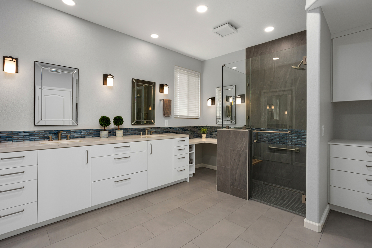 The bathroom after: white cabinetry, a blue glass tile band and a glass-enclosed shower