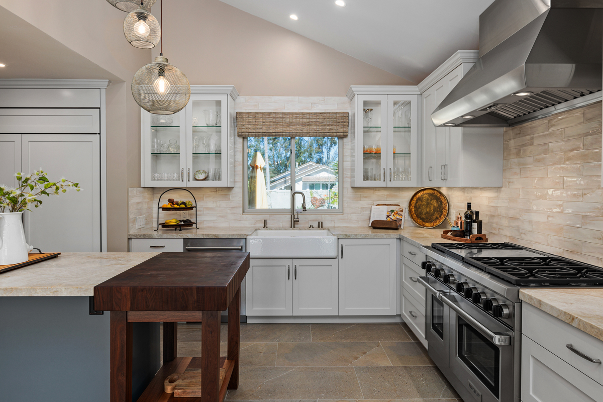 Kitchen with a pro range, glass-front cabinets, a butcher block island and pendant lights