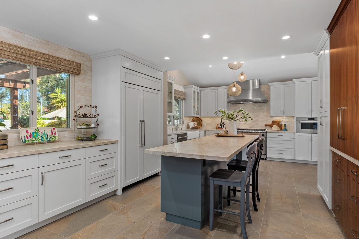 The kitchen after: white cabinetry, a blue-gray island and pale stone floors