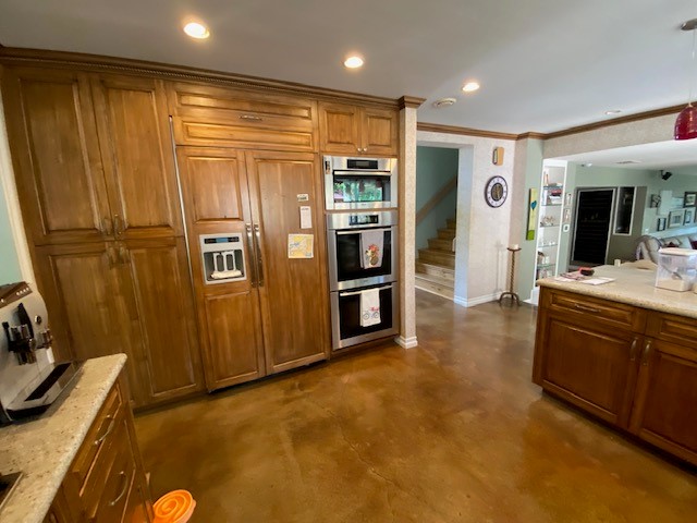 The kitchen before, with dark wood cabinets and brown floors