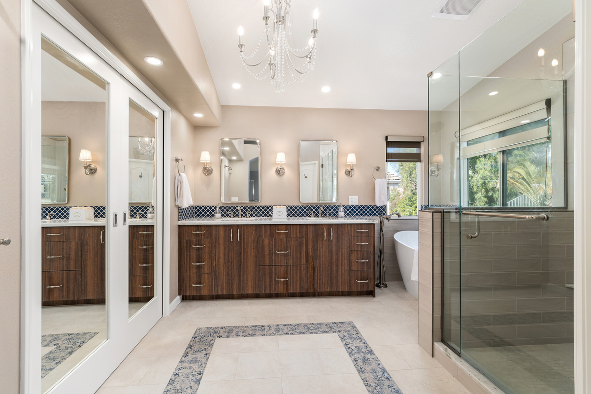 Primary bathroom with mirrored closet doors, a patterned tile floor and glass shower