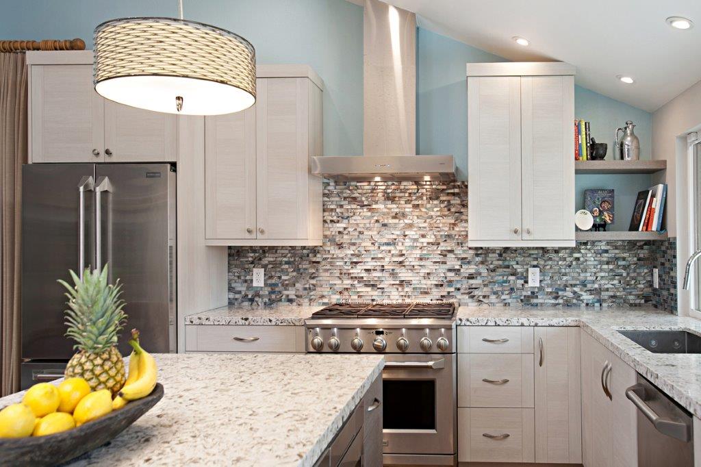 Kitchen with a shell mosaic backsplash, stainless range and a bowl of lemons on the counter