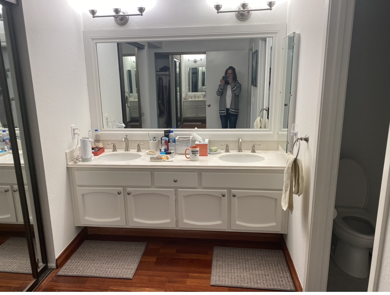 Before: a dated double vanity with a large frameless mirror and bar lights