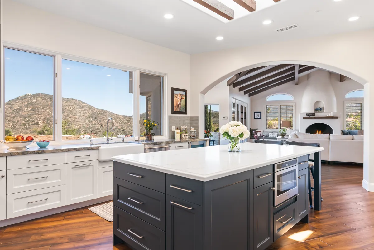 White kitchen with a navy island and a picture window framing the mountains