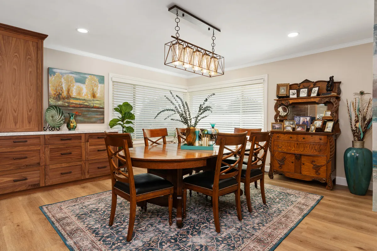 The dining room after: wood floors, a walnut sideboard and a linear chandelier