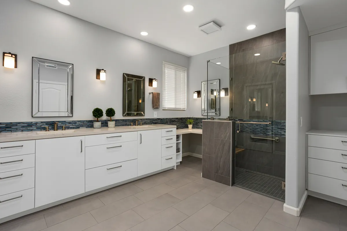 The bathroom after: white cabinetry, a blue glass tile band and a glass-enclosed shower