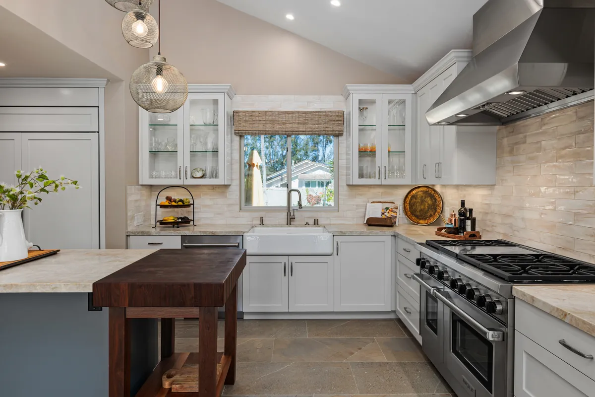 Kitchen with a pro range, glass-front cabinets, a butcher block island and pendant lights