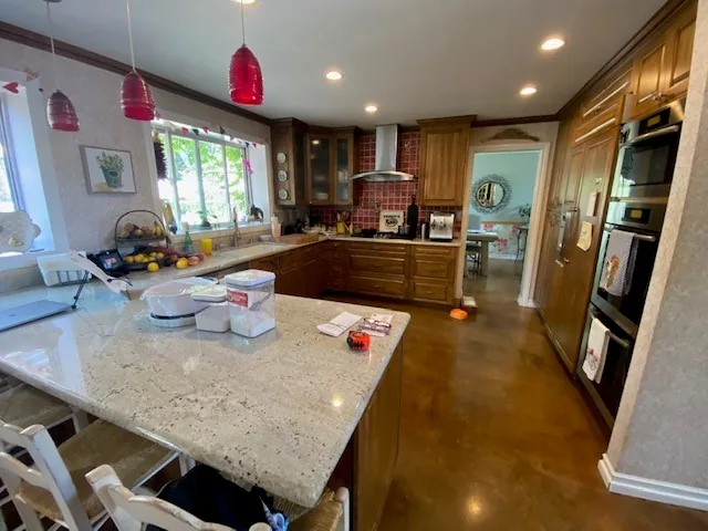 The kitchen before: dark wood cabinets, a granite island and red pendant lights